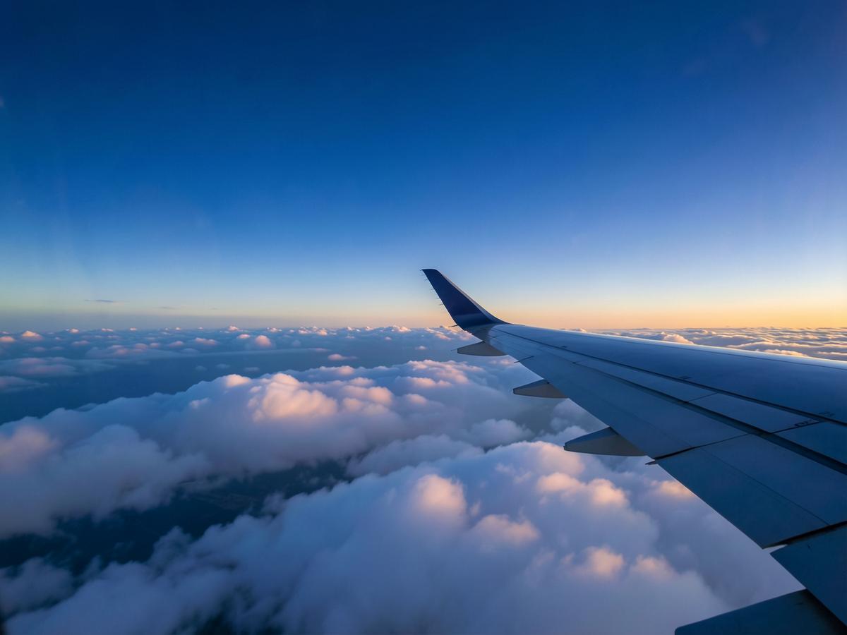 Airplane wing above the clouds at sunrise